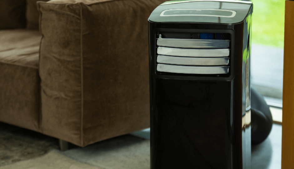 A black ok. air conditioning unit in a modern living room, a brown sofa in the background